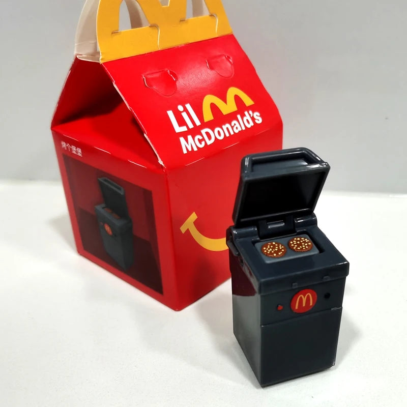 ألعاب بيت اللعب من ماكدونالدز، تشمل مجسمات مكونات المطعم، صناديق وجبات، ماكينات الطلب، وقبعات للأطفال، نموذج لعب واقعي